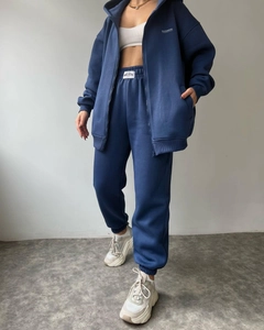 Detail view of navy blue hooded tracksuit with embroidered logos and jogger style