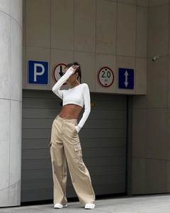 Detail of high-waisted khaki cargo trousers with large side pockets and loose fit