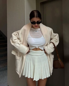Close-up of stylish off-white shearling jacket with mesh top and pleated skirt details