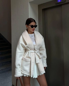 Detailed close-up of premium cream white shearling coat with fur lining and waist belt