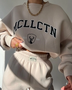 Detail of MCLLCTN branded logo embroidery on the beige fleece sweatshirt and jogger waist