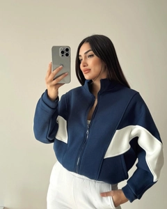 Close-up of contrast white wavy panel stitching on the sleeve of a blue zip-up jacket
