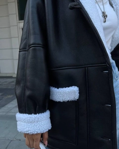 Detail of black faux leather jacket with plush white faux shearling trim and large pockets