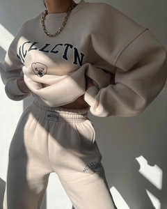 Detailed close-up of beige fleece lounge set featuring MCLLCTN logo print and brand labels