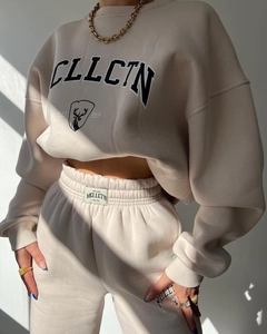 Detailed texture of thick beige hoodie fabric with CLLCTN lettering and deer logo