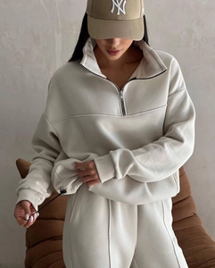 Detailed view of beige tracksuit featuring half-zip collar and adjustable hem drawstring