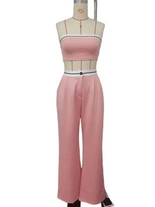 Detail of pink crop tank top and wide leg pants with striped trim and black button