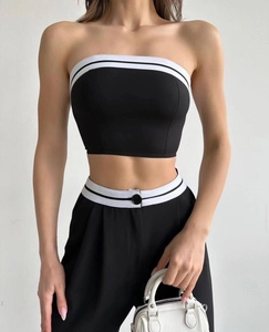 Detail of high waist trousers and tube top with contrast white stripe and button accents