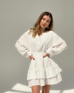Close-up of white V-neck dress featuring textured fabric and ruffled hem details