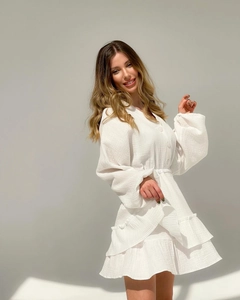 Detail view of white V-neck dress with button decor and layered ruffle hemline