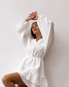 Detail of white V-neck dress with buttons, elastic waist, and lantern sleeves texture