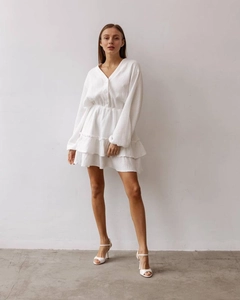 Detail view of the V-neckline and button-up front on this white A-line mini dress