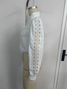 Detail of white long sleeve blouse featuring hollow ring lace embroidery on sleeves