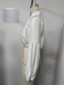 Détail du chemisier blanc court à manches bouffantes montrant le tissu texturé et la taille