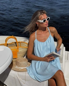 Detail of light blue summer slip dress paired with a woven straw bag on a boat