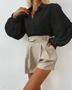 Detail of long sleeve shirt with lace cut-outs paired with high waist buttoned shorts