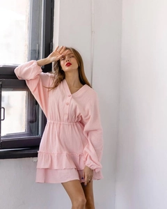 Close-up of pink V-neck dress with buttons, smocked waist, and ruffle hem detail