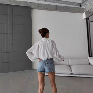 Vue arrière du chemisier blanc à manches bouffantes et short en jean taille haute