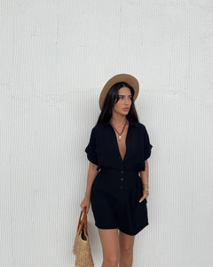 Detail of a black short sleeve romper with a deep V-neckline and front buttons