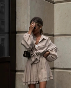 Detail of beige long sleeve shirt with waist tie and matching tiered shorts set