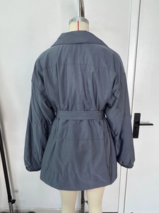 Back view of dark gray-blue quilted winter coat with adjustable waist belt and lapel collar