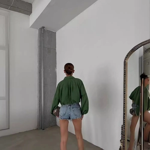 Détail du chemisier vert à manches bouffantes porté avec un short en jean usé