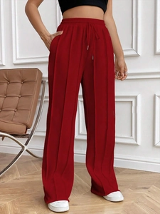 Détail du pantalon rouge taille haute à cordon de serrage avec texture côtelée fluide