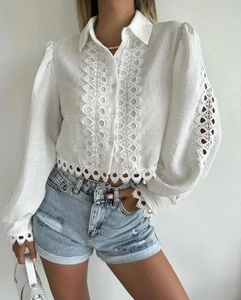 Detail of white cotton shirt featuring intricate lace cutouts and puff sleeves design