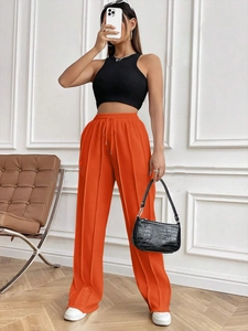 Détail du pantalon orange à taille haute avec cordon de serrage et texture verticale