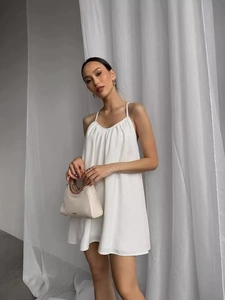 Elegant white summer mini dress with thin straps and ruffled neckline for beach wear