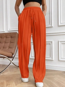 Détail d'un pantalon de jogging taille haute orange vif avec cordon et plis verticaux