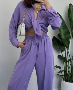 Detail of lilac purple pleated fabric on long sleeve tie-front shirt and matching trousers