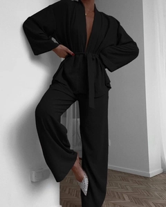 Detail of black tie-waist wrap top and wide-leg trousers set with textured fabric