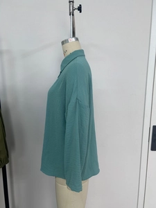Detailed view of teal long sleeve shirt showing textured seersucker fabric and side slit