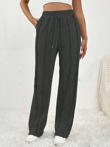 Détail du pantalon large gris foncé avec coutures verticales et ceinture à cordon réglable