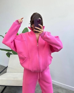 Detail of oversized bright pink fleece tracksuit featuring a hooded zipper and ribbed cuffs