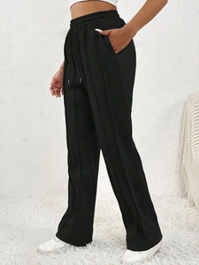 Détail du pantalon de jogging noir à taille haute avec cordon de serrage et couture verticale