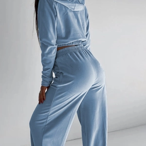 Dettaglio laterale di un set in velluto azzurro con felpa con cappuccio e pantaloni ampi