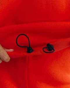 Detail of black adjustable drawstring toggles on heavy red knit cotton tracksuits