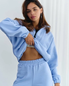 Detail of light blue two-piece tracksuit featuring a half-zip sweatshirt and high-waist pants