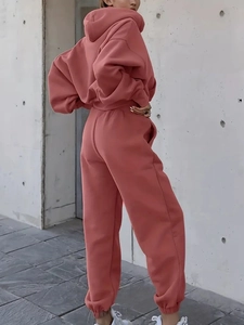 Outdoor side-back view of brick red hoodie and sweatpants set on industrial background