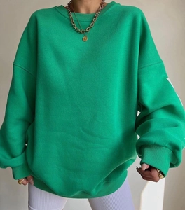 Detail of green oversized sweatshirt showing ribbed cuffs and sleeve graphic print