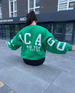 Detail view of oversized green sweatshirt with white Chicago print on the back and sleeves