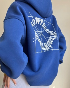 Detail of blue hoodie with white 'GROW THROUGH' text and spider web pattern on back