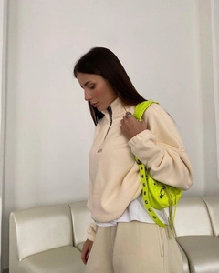 Detail of beige fleece sweatshirt with half-zip stand collar and chest embroidery