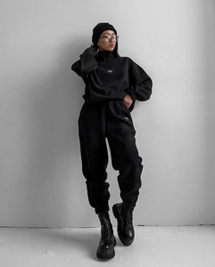 Detail eines schwarzen Oversize-Trainingsanzugs mit Reißverschluss-Stehkragen und Kordelzug-Hose