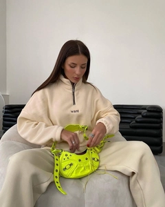 Detail of off-white fleece half-zip sweatshirt with 'want' embroidery and neon handbag