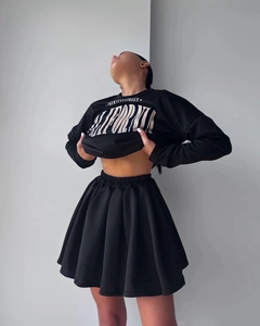 Detail of black two-piece set featuring California graphic sweatshirt and pleated mini skirt