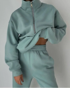 Dettaglio del tessuto della felpa verde salvia con zip e pantaloni sportivi a vita alta