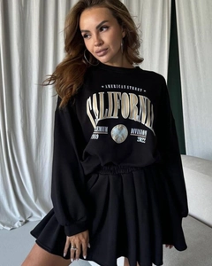 Close-up of California eagle print on black sweatshirt with pleated mini skirt texture